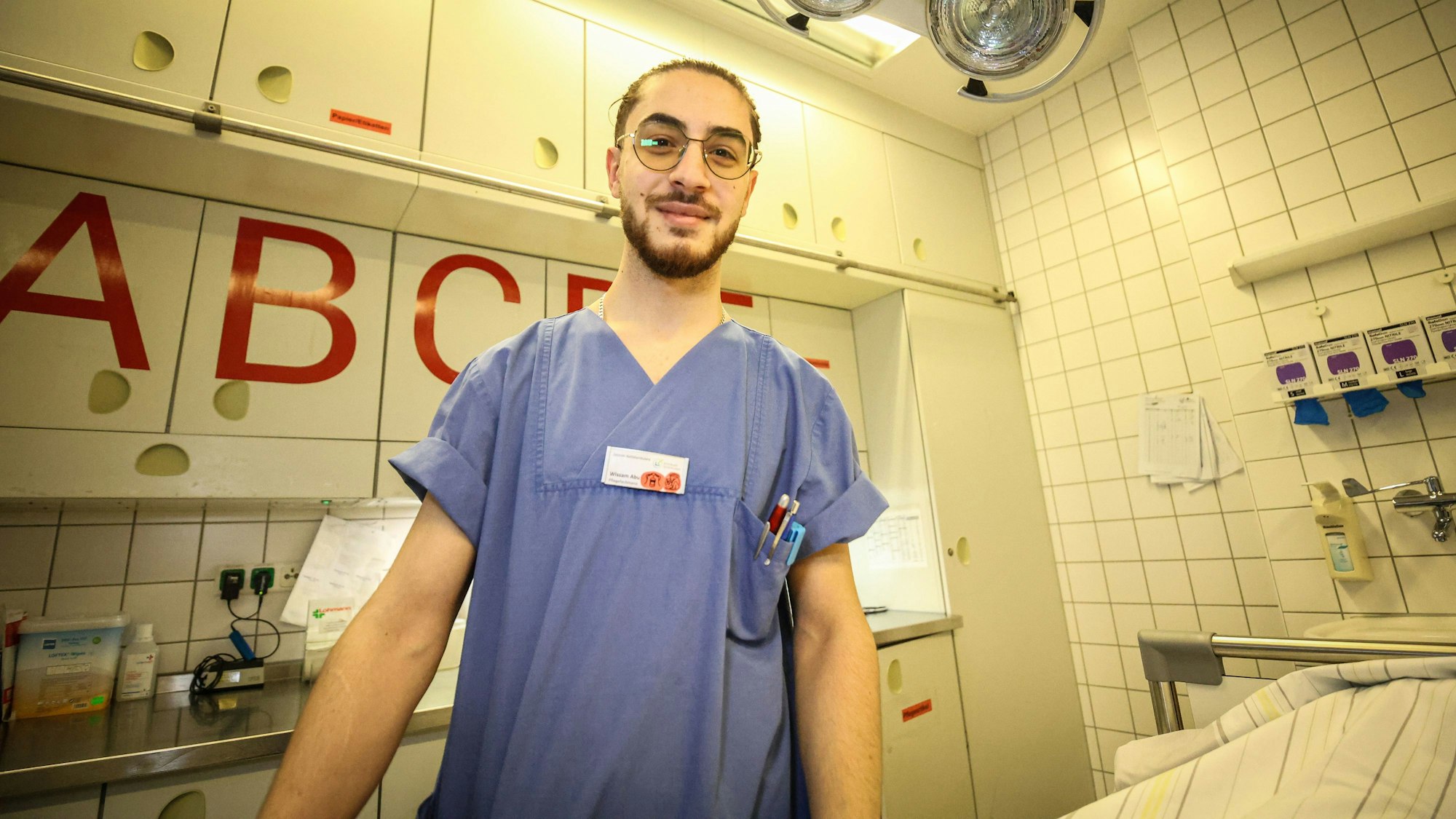 Wissam Abu Alneay ist Pfleger im Klinikum Leverkusen und in einem Behandlungsraum im Halbporträt zu sehen.