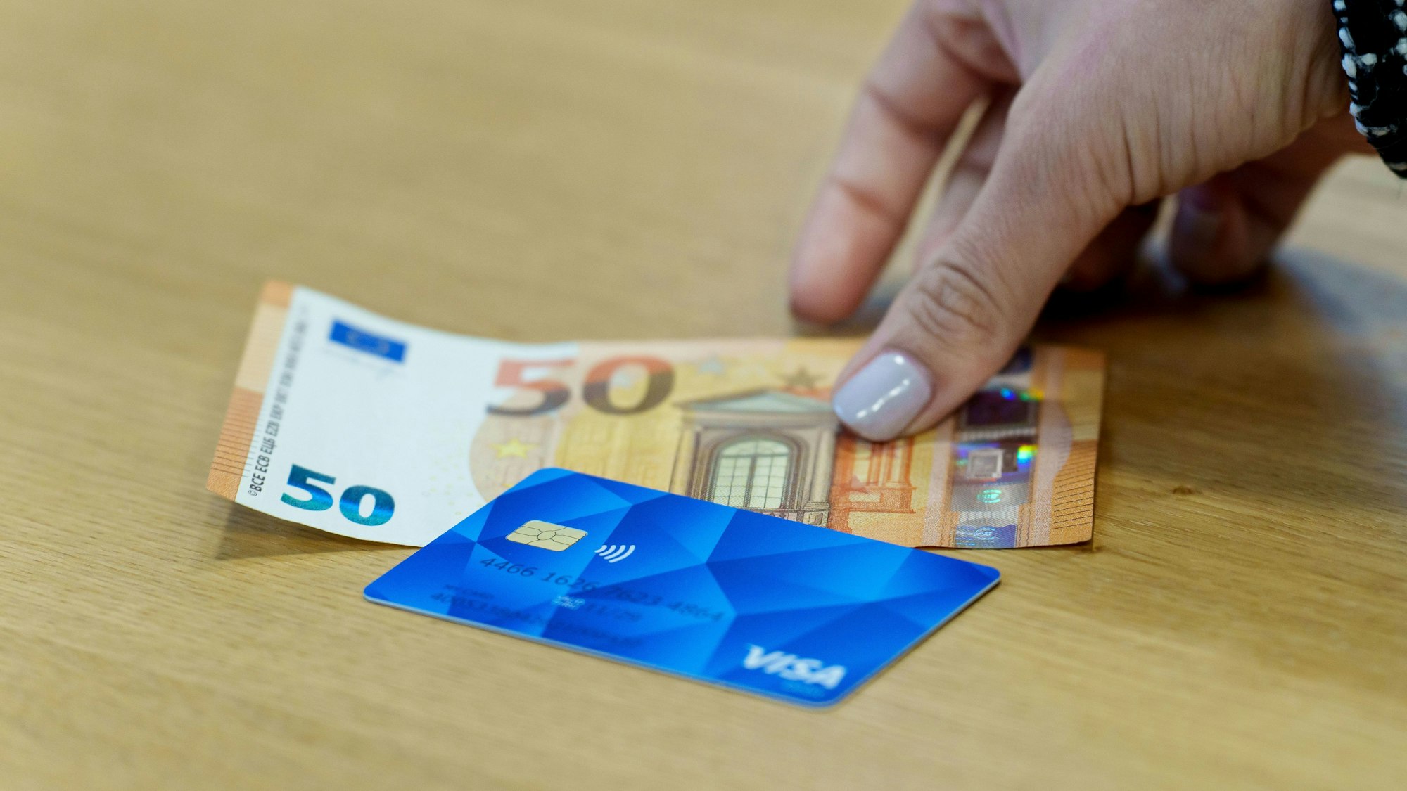 ARCHIV - 13.12.2024, Hessen, Wiesbaden: ILLUSTRATION - Eine Bezahlkarte für Asylbewerberinnen und Asylbewerber und ein 50-Euro-Schein liegen nebeneinander. (zu dpa: «Land stoppt Wiesbaden bei Asylbewerber-Bezahlkarte») Foto: Andreas Arnold/dpa +++ dpa-Bildfunk +++