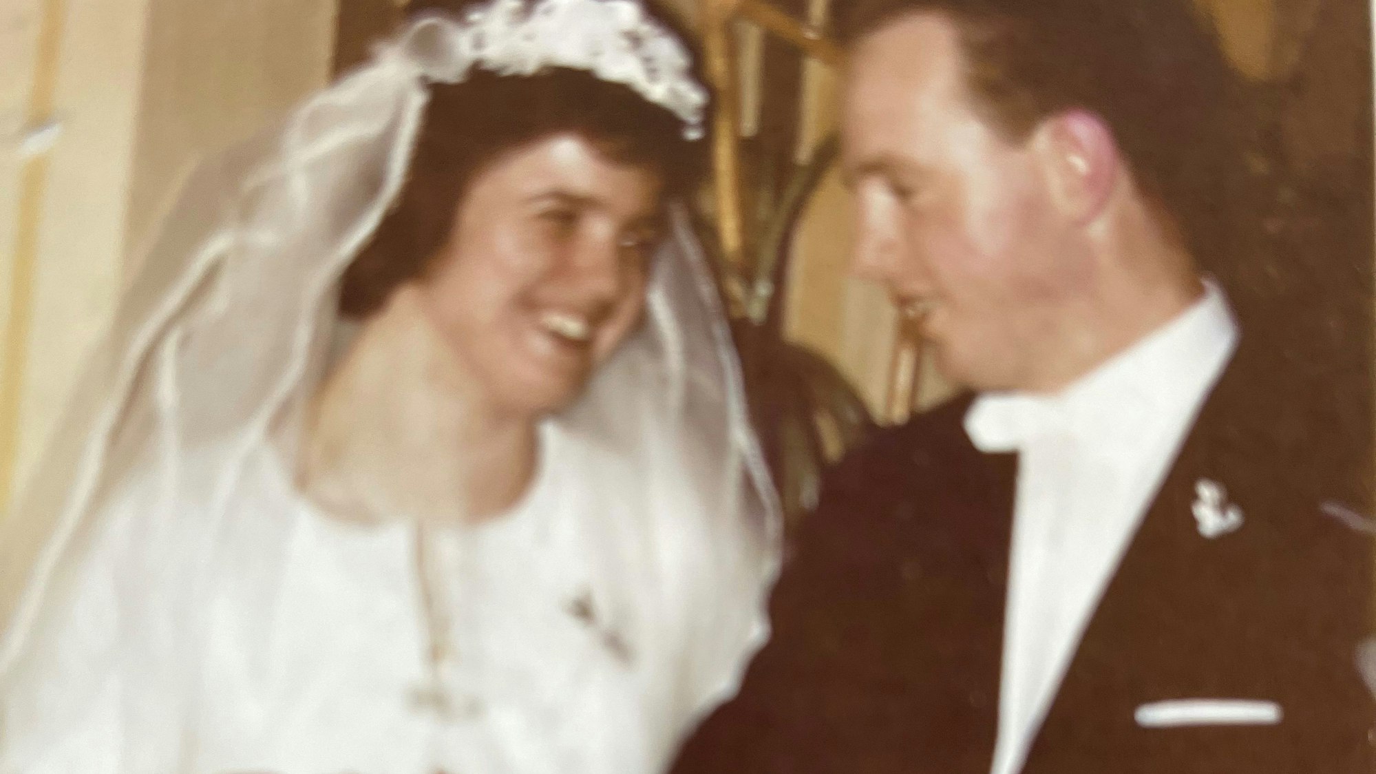 Die Braut mit Schleier lächelt ihren Mann an.