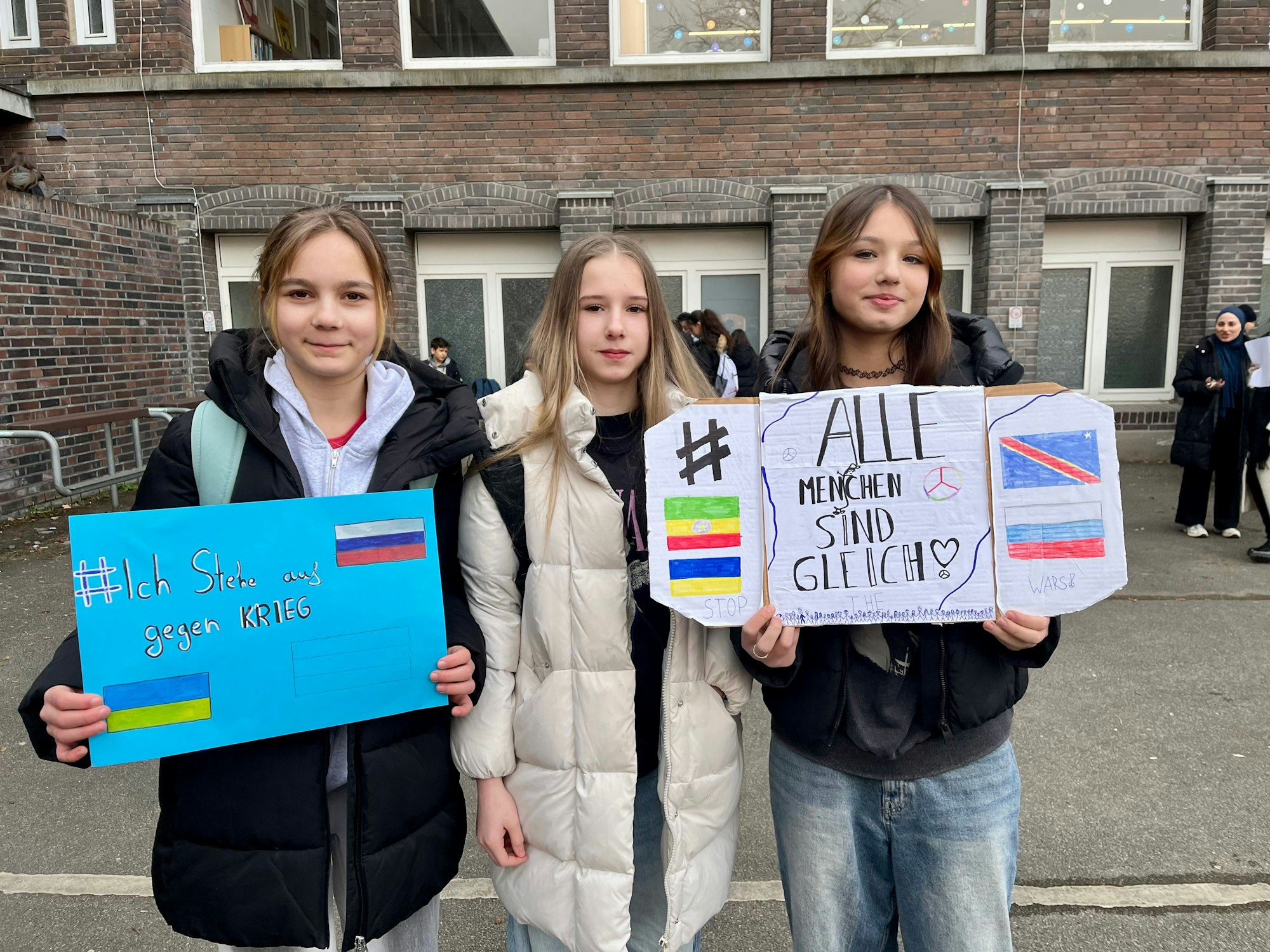 Drei Mädchen mit Plakaten.