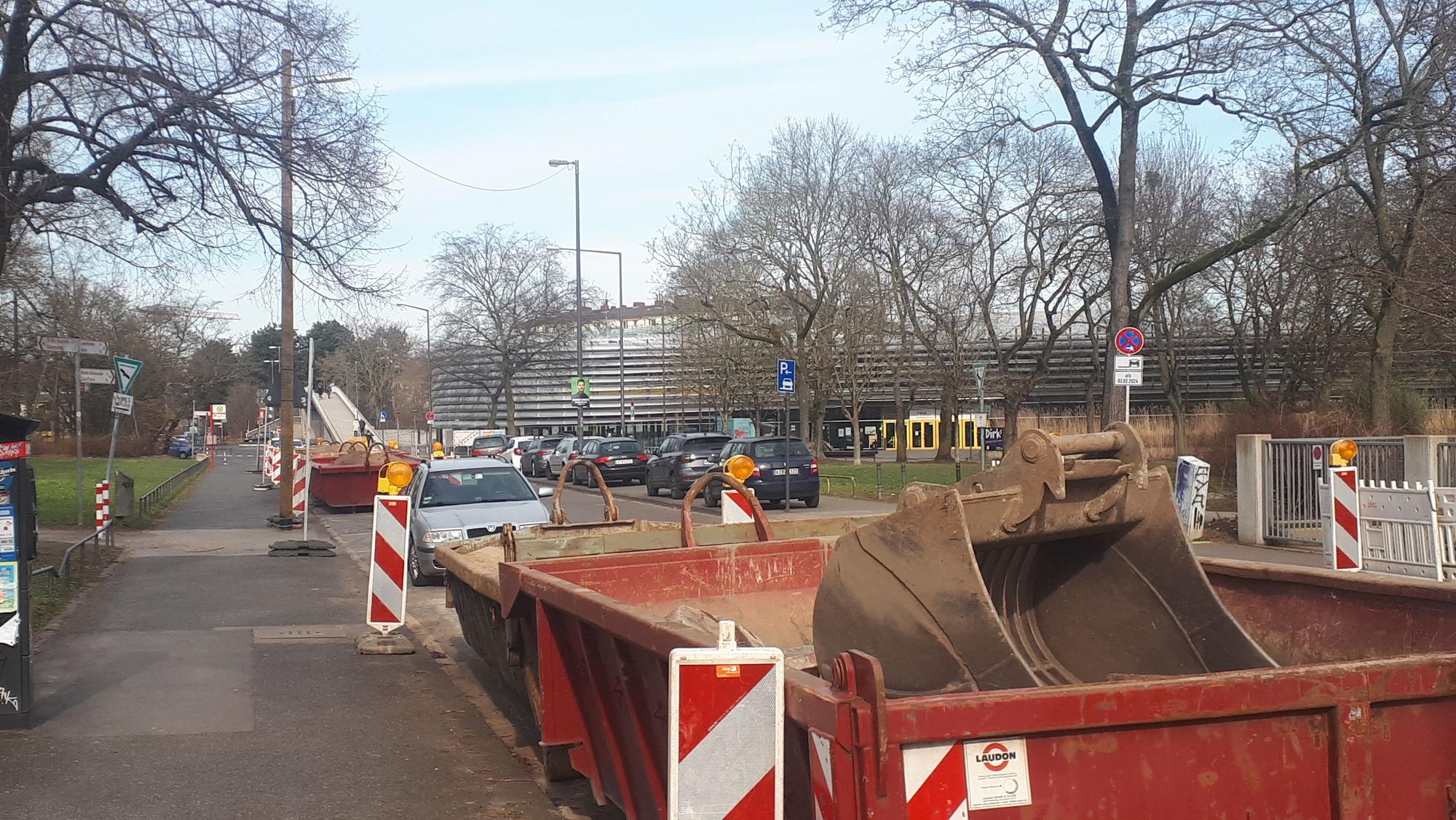 Eine Baustelle in der Innenstadt. Am Straßenrand stehen Bauschuttcontainer und Leitbaken.