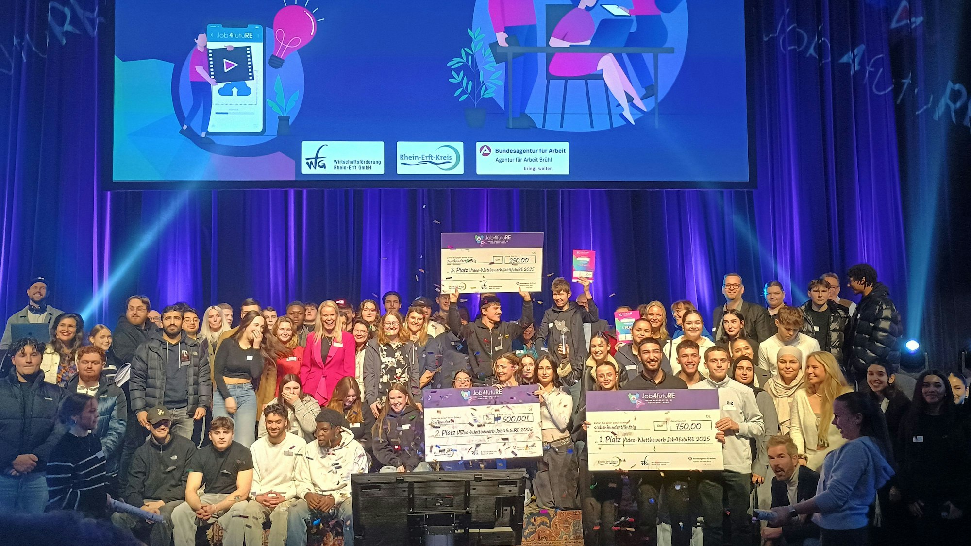 Auf dem Bild sind zahlreiche Berufsschüler aus dem Kreis im Medio Rhein Erft zu sehen, die Gewinnerteams halten die Schecks mit ihrem Preisgeld hoch.