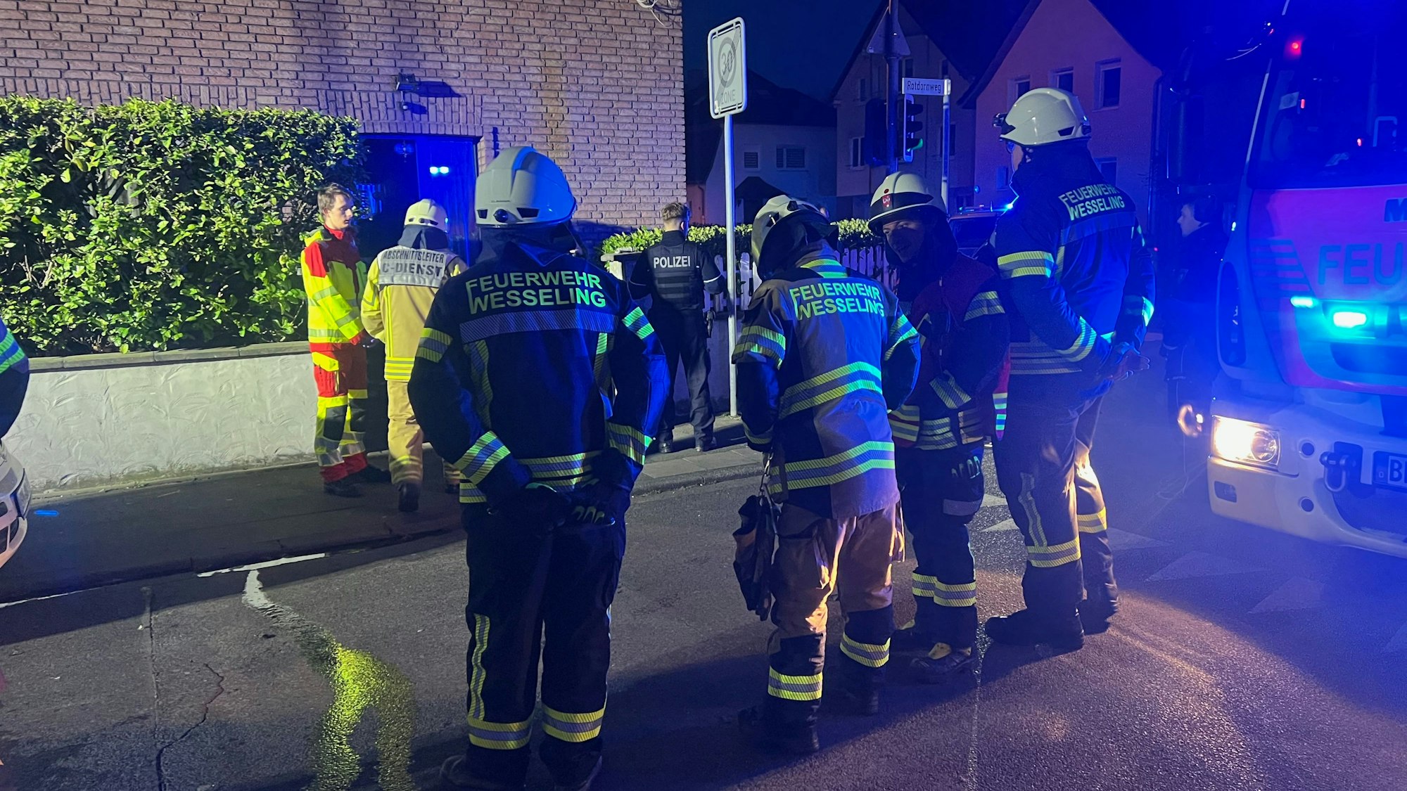 Feuerwehrleute stehen vor einem Wohnhaus in Wesseling, in dem ein Feuer in einer Küche ausgebrochen ist.