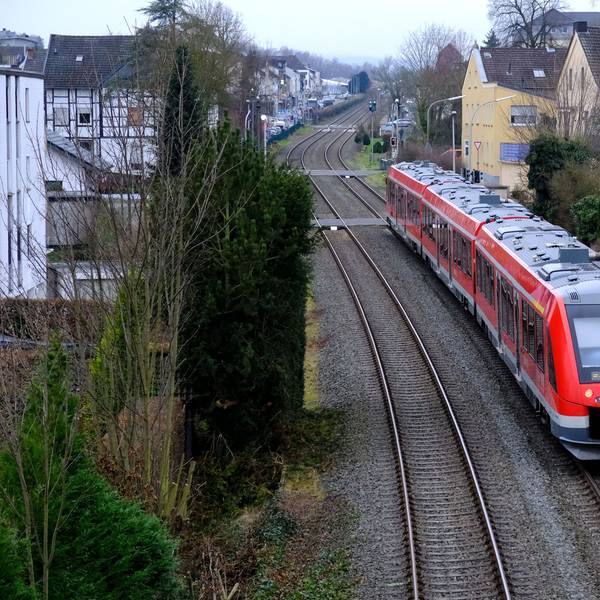Ein roter Vareo-Nahverkehrszug befährt die Eifelstrecke bei Mechernich.