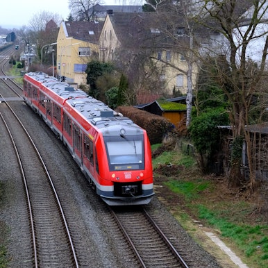 Ein roter Vareo-Nahverkehrszug befährt die Eifelstrecke bei Mechernich.