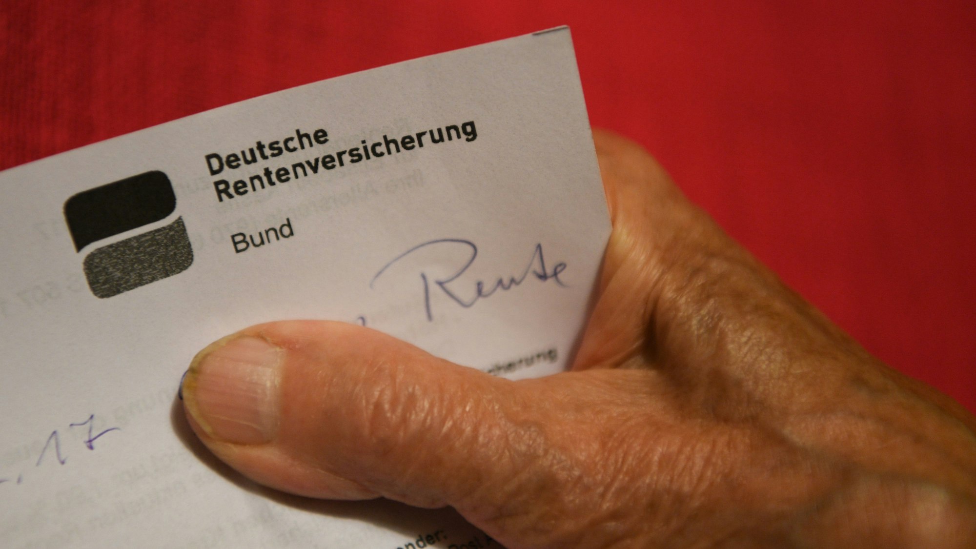 Eine Rentnerin hält ihren Rentenbescheid in der Hand.