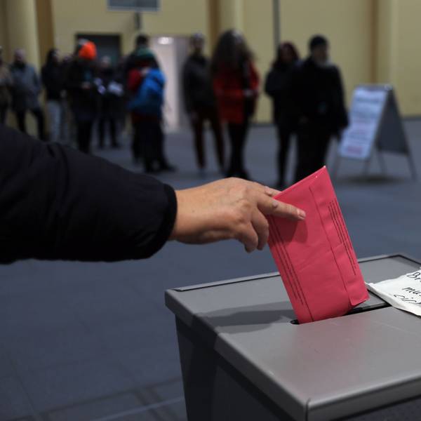 Eine Person wirft einen Stimmzettel in eine Wahlurne.