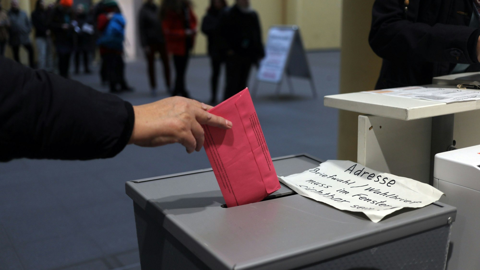 Eine Person wirft einen Stimmzettel in eine Wahlurne.