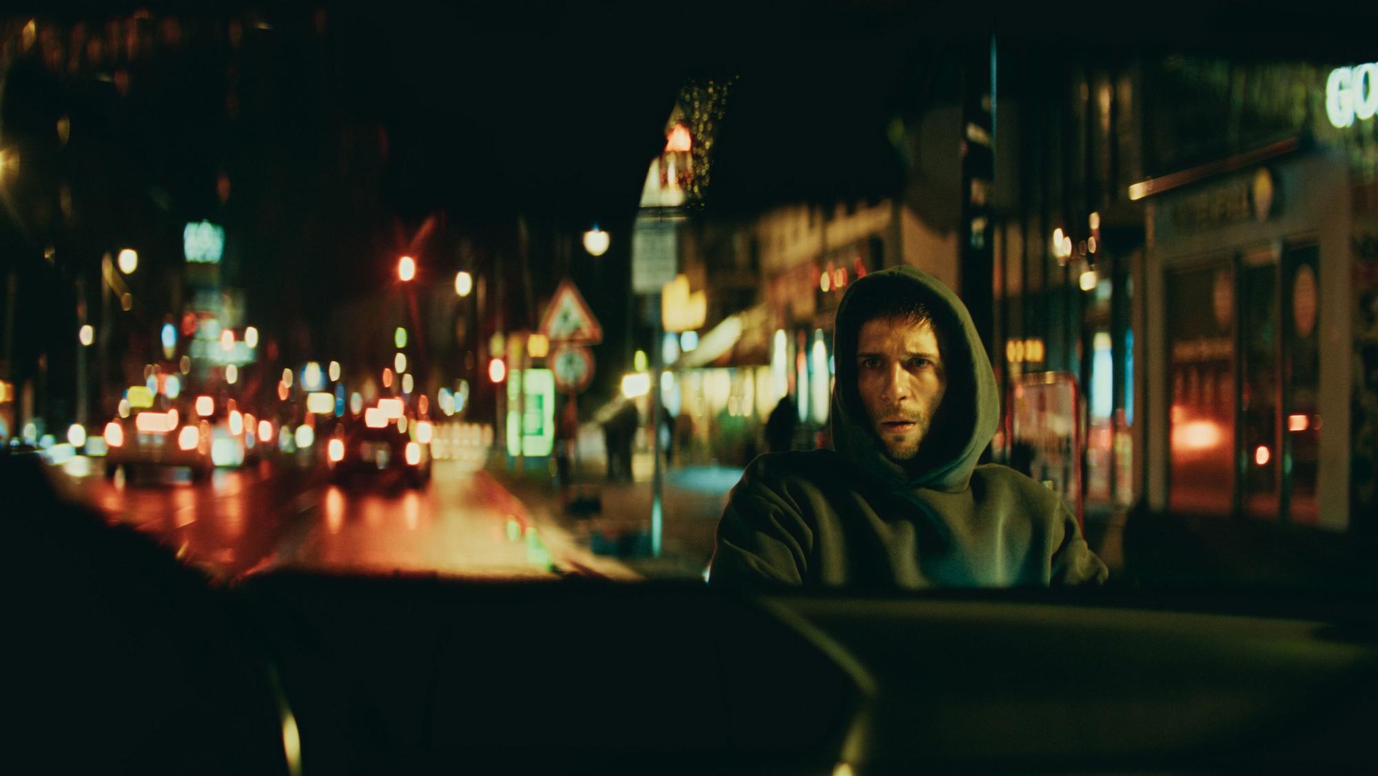 Slavko Popadić mit Kapuzenpullover nachts auf den Straßen Berlins.