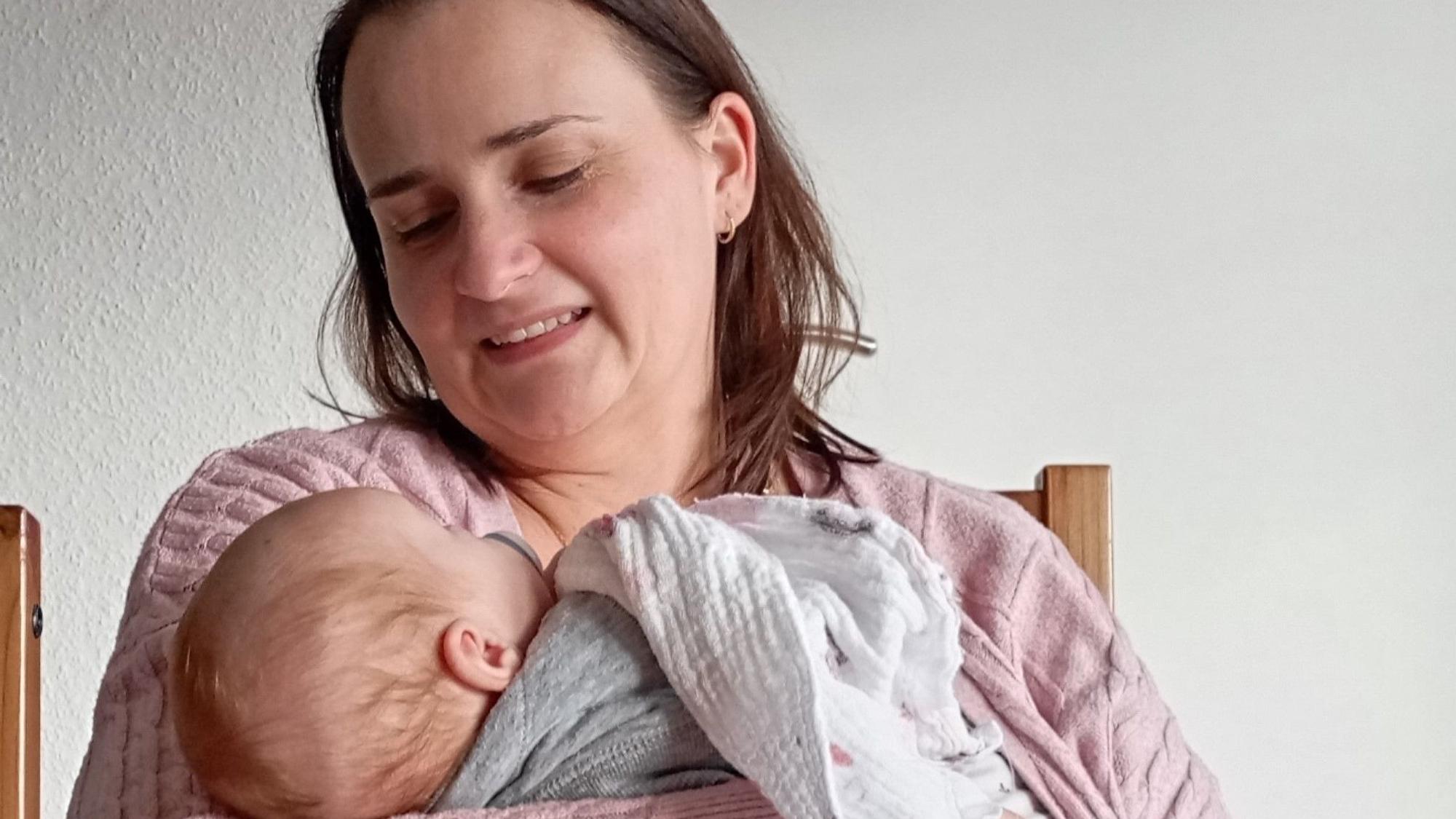 Das Foto zeigt eine Pflegemutter mit einem Säugling auf dem Arm.