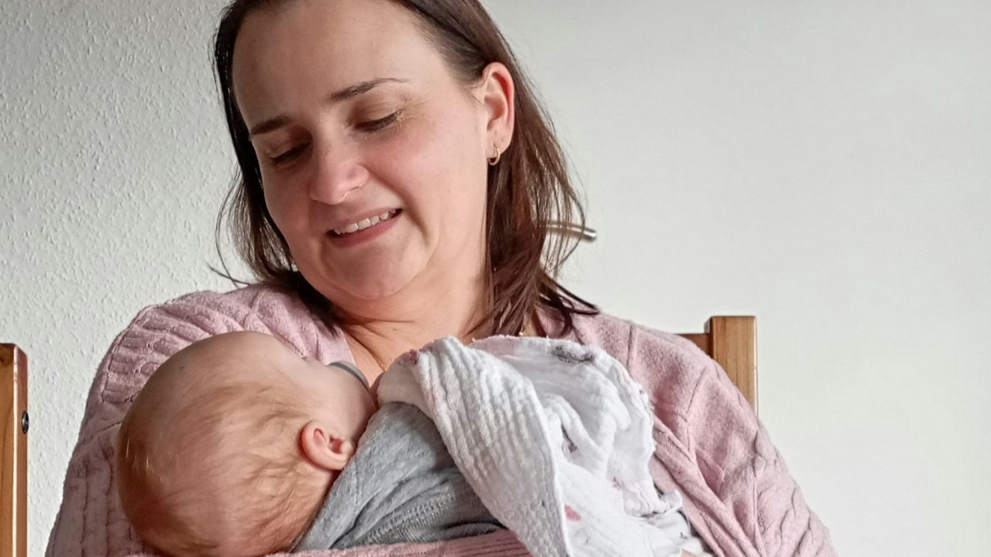 Das Foto zeigt eine Pflegemutter mit einem Säugling auf dem Arm.