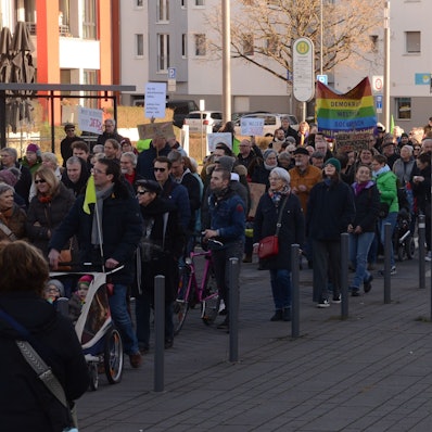 Menschen mit Flaggen und Schildern auf einer Demonstration in Troisdorf.