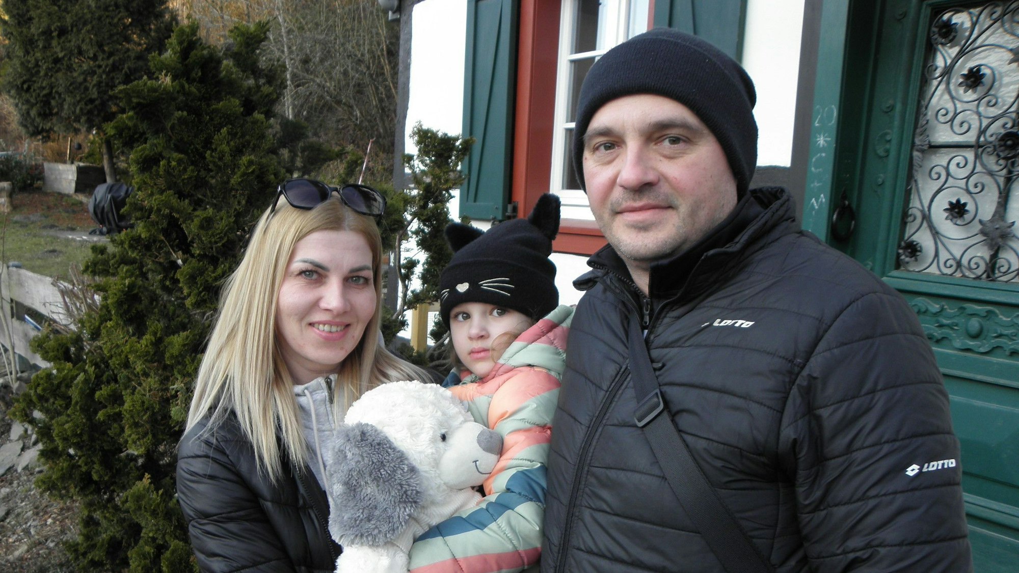 Anna Dehtiarinska, ihr Mann Denys Dehtiarinsky und ihre Tochter stehen vor einem Eifeler Fachwerkhaus.