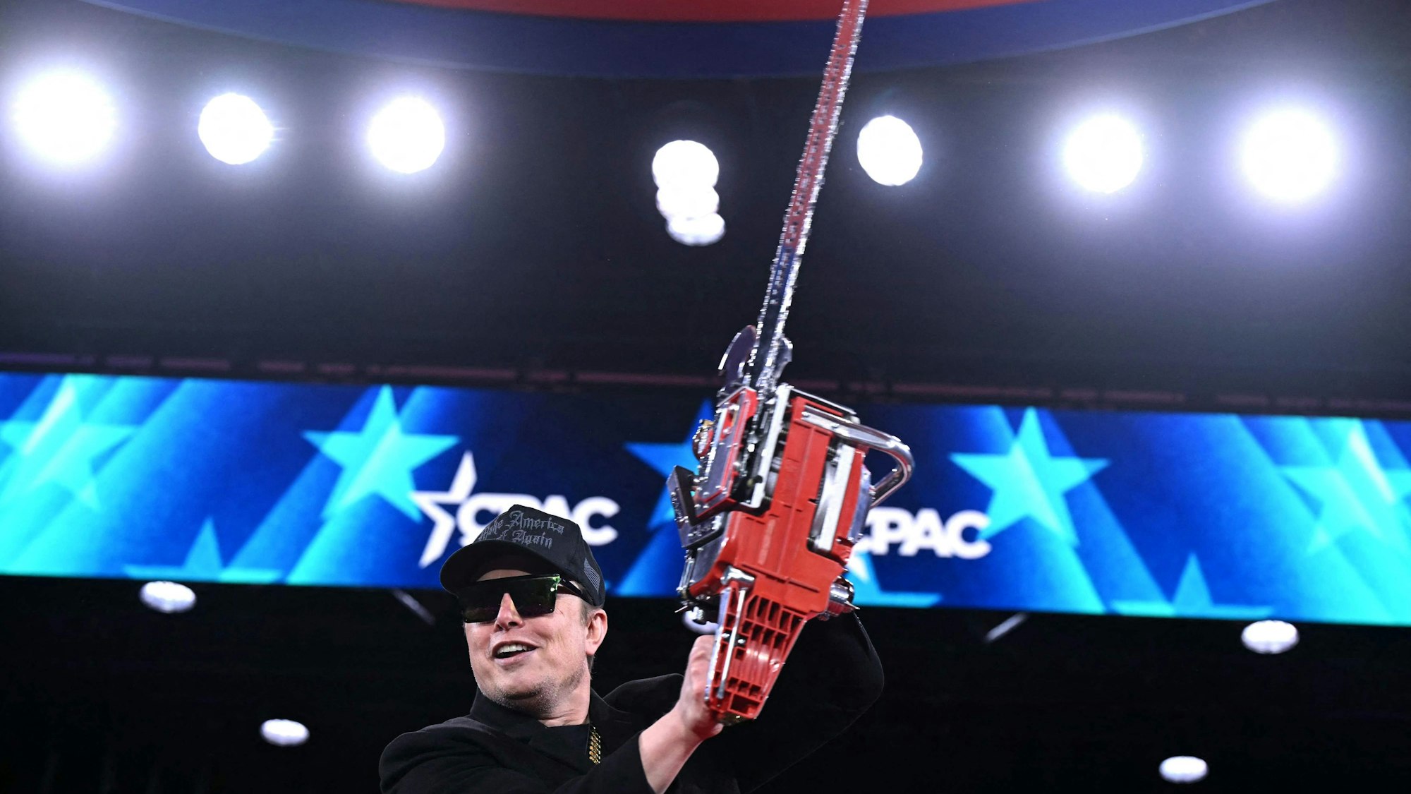 Elon Musk mit einer Kettensäge auf der Bühne.