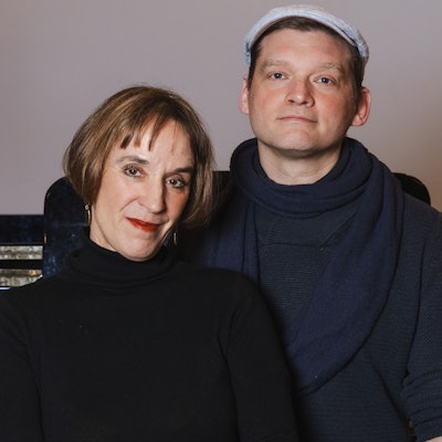 Eine Frau mit Pagenschnitt und ein Mann mit Schiebermütze.