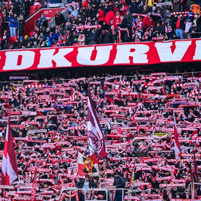 Fans des FC Bayern München halten in der Südkurve vor einem Spiel Fanschals in die Luft.