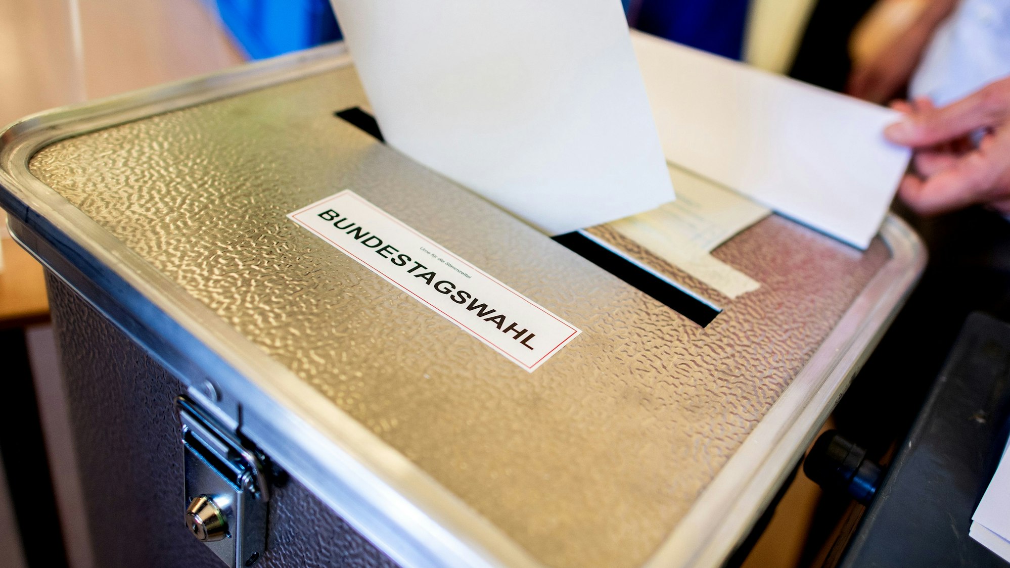 Ein Wähler wirft in einem Wahllokal, das im Klassenraum einer Grundschule im Stadtteil Prenzlauer Berg untergebracht ist, seinen Stimmzettel für die Bundestagswahl in eine Wahlurne.