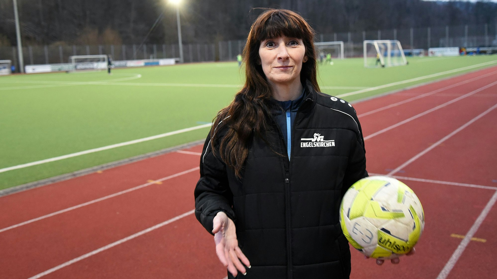 Sabine Kalwellis im Porträt auf dem Fußballplatz in Engelskirchen. In einer Hand hält sei einen Fußball.