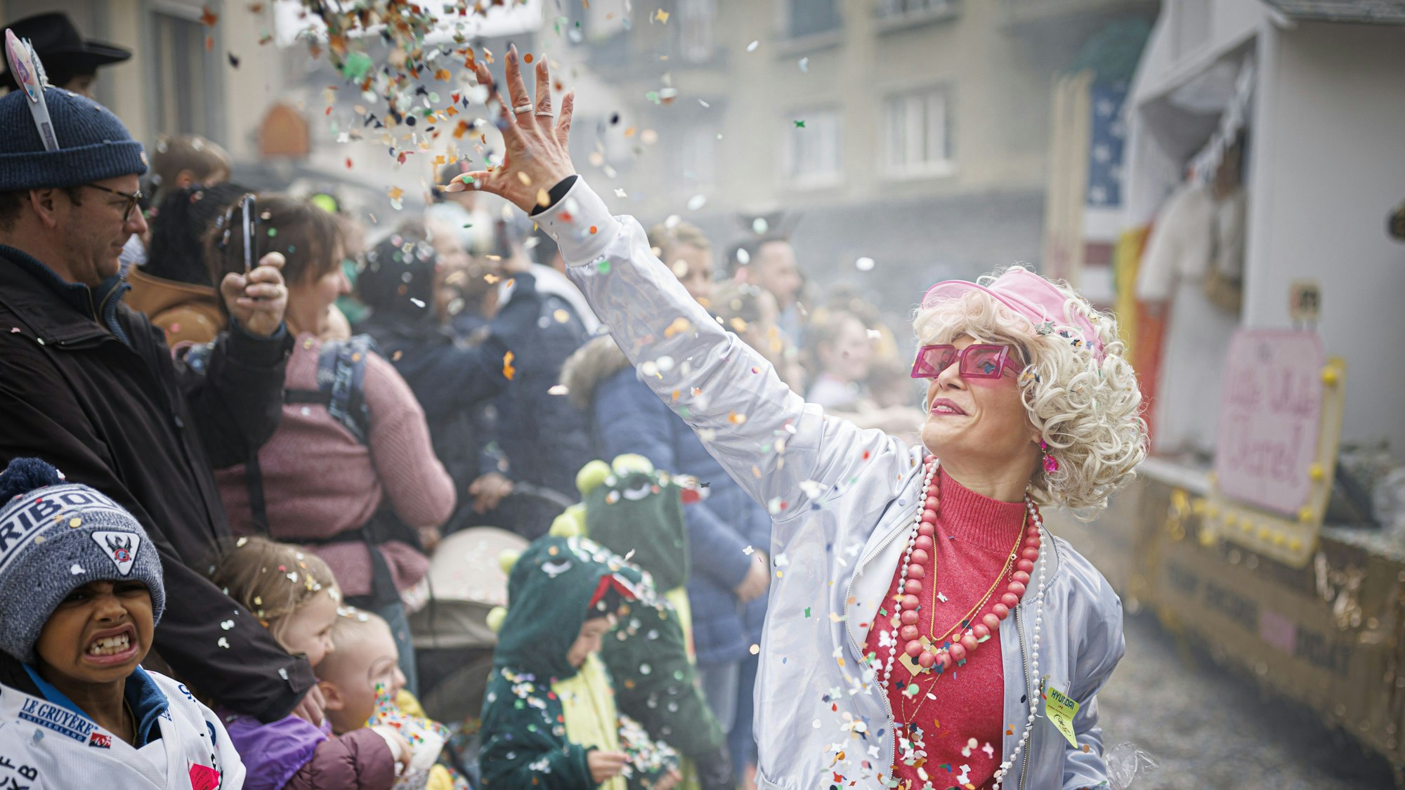 Eine Feiernde wirft Konfetti in die Menge bei einem Karnevalsumzug.