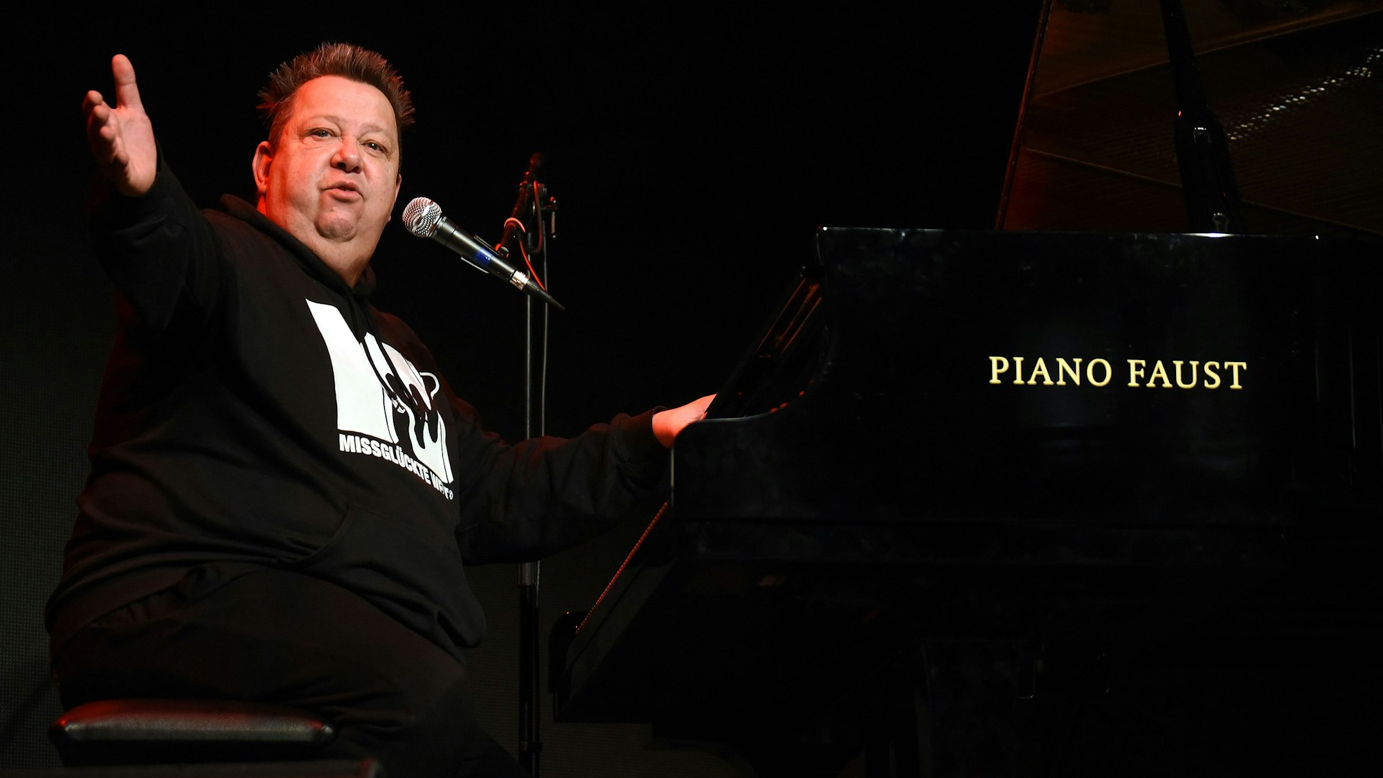 Sebastian Krumbiegel sitzt am Piano und hat die Arme weit ausgebreitet.