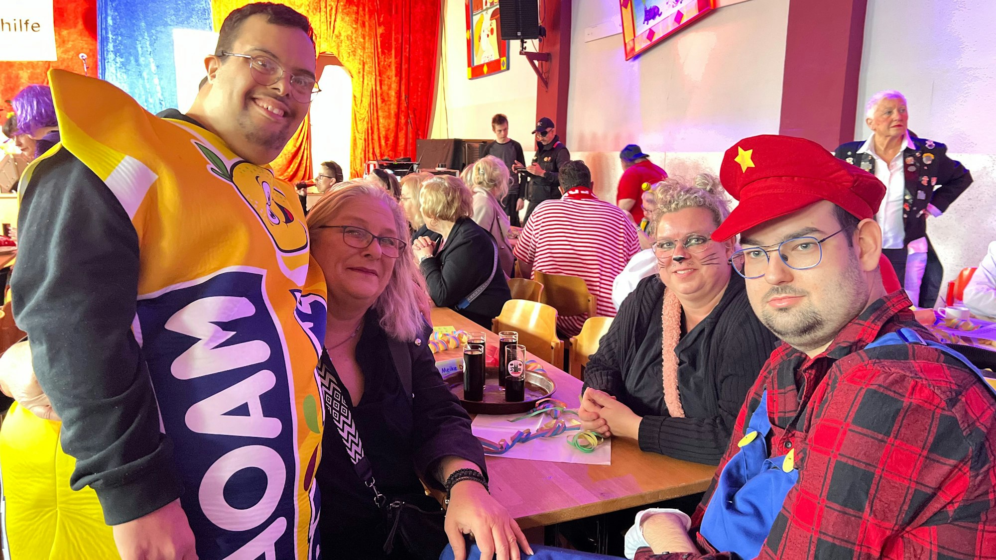 Verkleidete Männer und Frauen feiern Karneval in einem Saal.