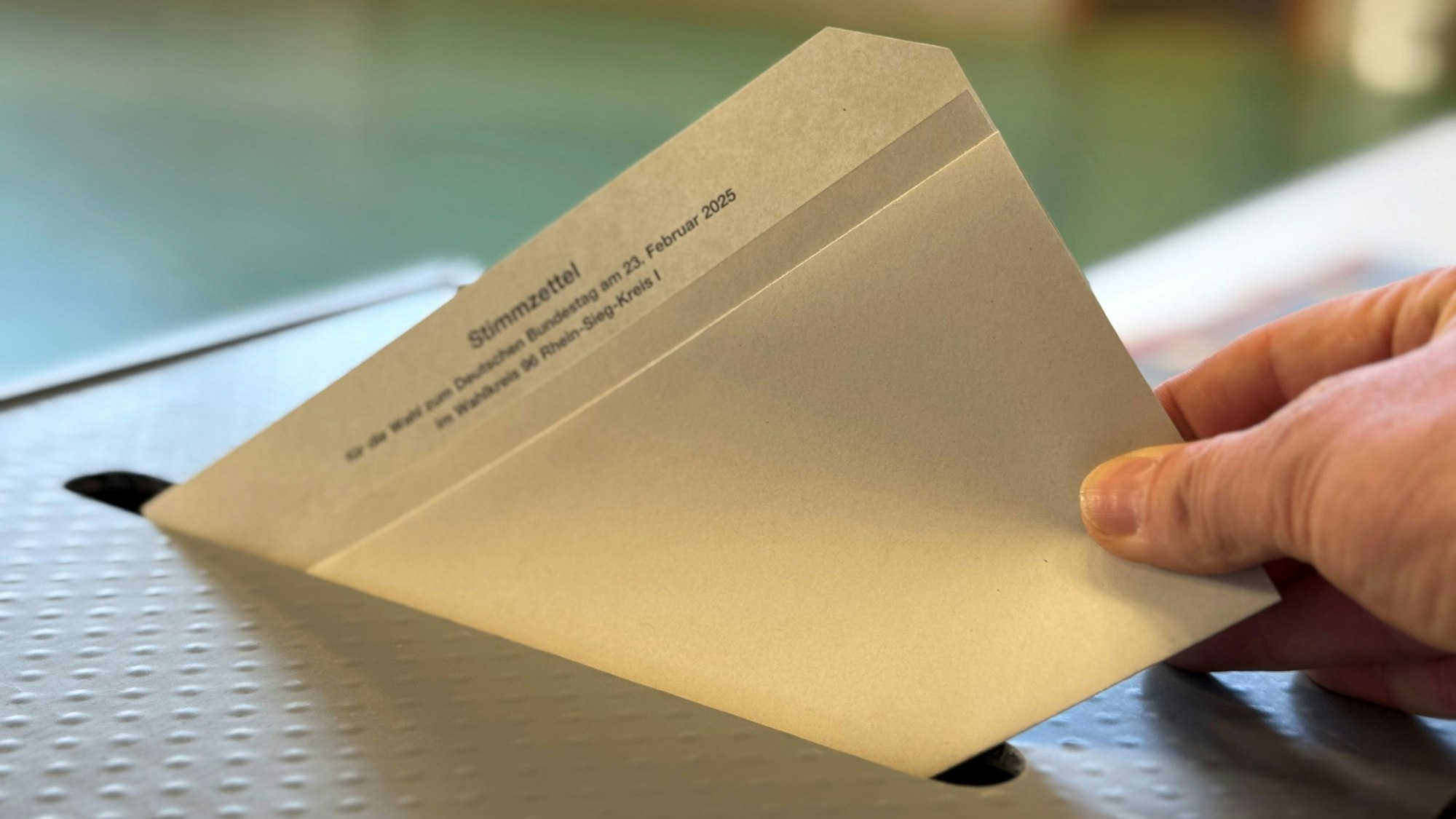 Eine Hand wirft einen Wahlzettel in die Urne.