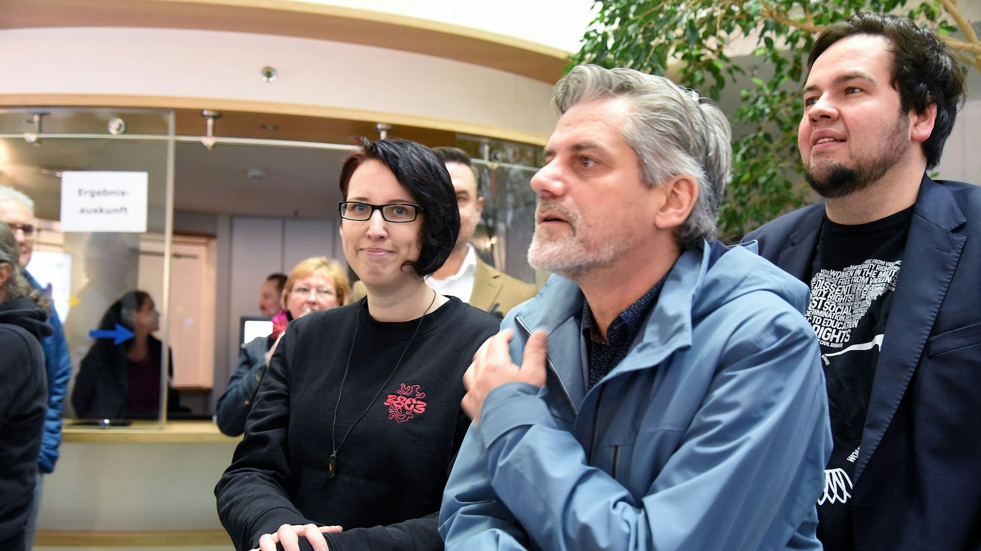 Die Grünen-Abgeordnete Sabine Grützmacher steht mit weiteren Fraktionsmitgliedern im Kreishaus und schaut auf die Wahlprognose.