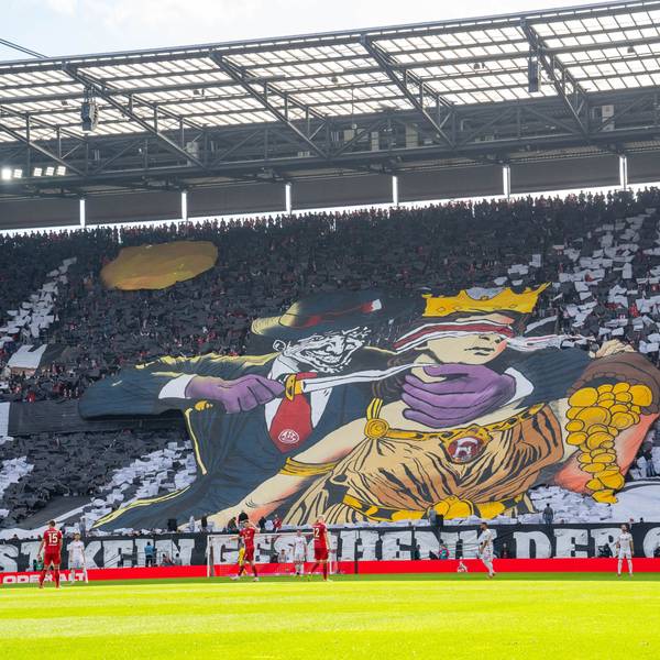 Ein Transparent, das Kölner Fans im Rhein-Energie-Stadion entfalteten, zeigt eine Comic-Figur, die einer Frau mit verbundenen Augen ein Messer an den Hals hält. Die Frau ist der Göttin Fortuna nachempfunden und schüttet Gold aus einem Füllhorn.
