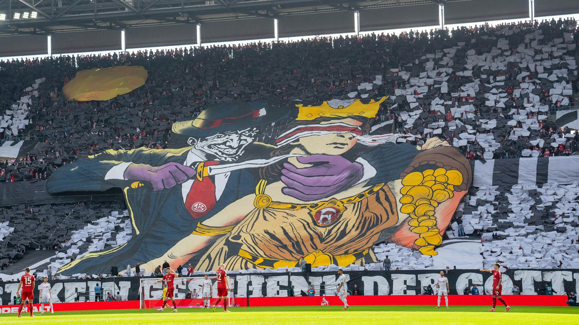 Ein Transparent, das Kölner Fans im Rhein-Energie-Stadion entfalteten, zeigt eine Comic-Figur, die einer Frau mit verbundenen Augen ein Messer an den Hals hält. Die Frau ist der Göttin Fortuna nachempfunden und schüttet Gold aus einem Füllhorn.