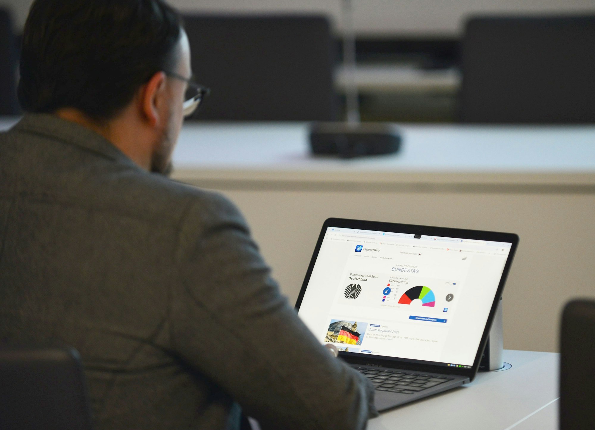 Das Bild zeigt eine Person vor einem Laptop, auf dem die Prognosen der Wahl gezeigt werden.