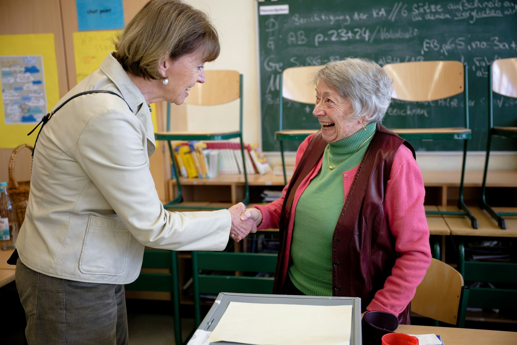 23.02.2025, Nordrhein-Westfalen, Köln: Henriette Reker (parteilos, l), Oberbürgermeisterin von Köln, bedankt sich bei Lydia Mörs-Plattes, mit 100 Jahren Kölns älteste Wahlhelferin, in einem Wahllokal in Köln-Rondorf für ihren Einsatz. Mörs-Plattes hat zum Dank von Reker den Karnevalsorden der Stadt Köln erhalten. Am Sonntag findet die vorgezogene Wahl zum 21. Deutschen Bundestag statt. Foto: Henning Kaiser/dpa +++ dpa-Bildfunk +++