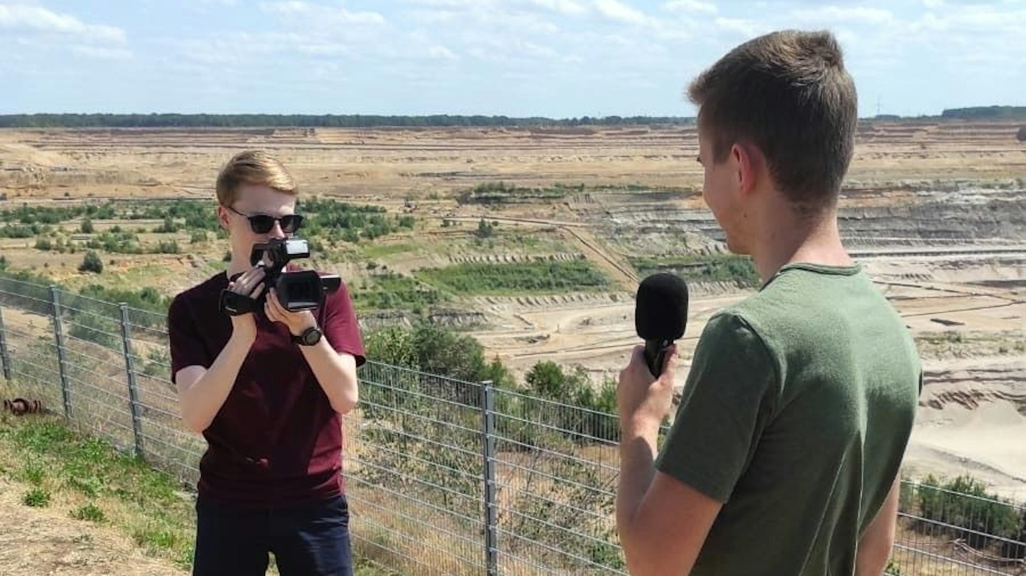 Das Foto zeigt zwei junge Männer bei einem Videodreh vor dem Tagebau Hambach.