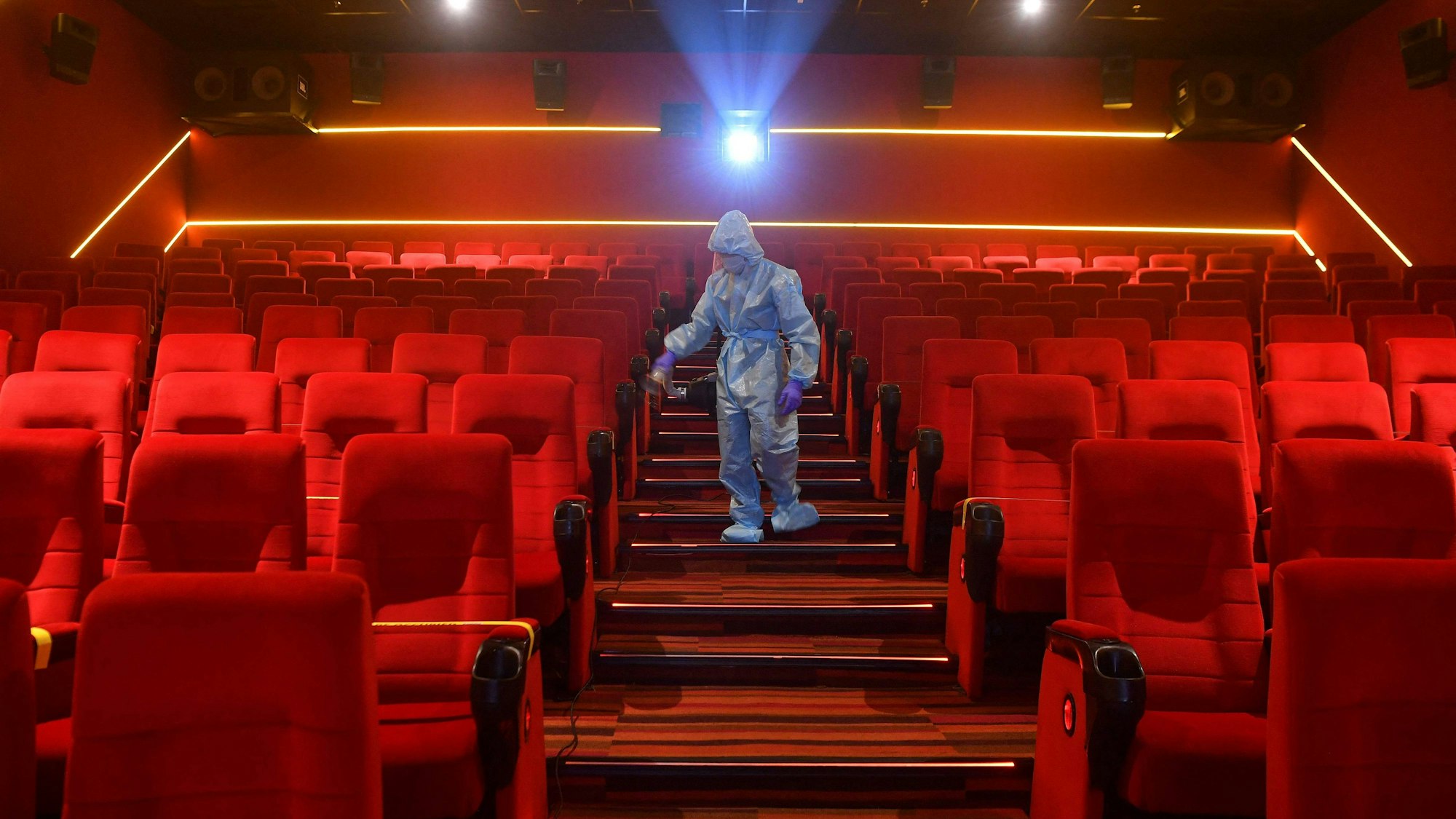 Ein Mitarbeiter desinfiziert die Sitze in einem Kinosaal.