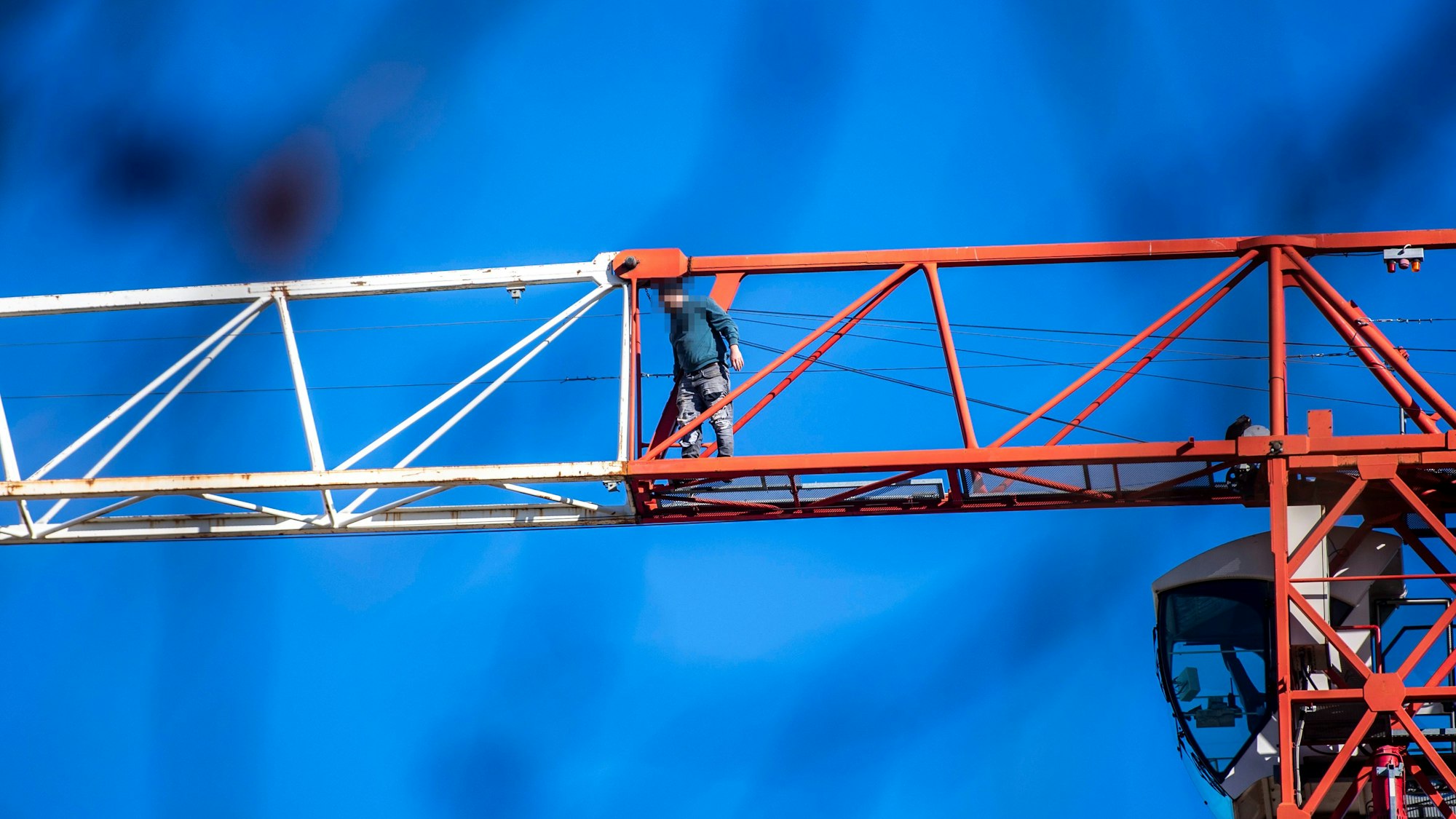 Das Bild zeigt den Mann, der ungesichert auf dem Ausleger des Krans steht.