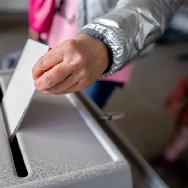 Eine Wählerin wirft in einem Wahllokal einen Stimmzettel in eine Wahlurne.