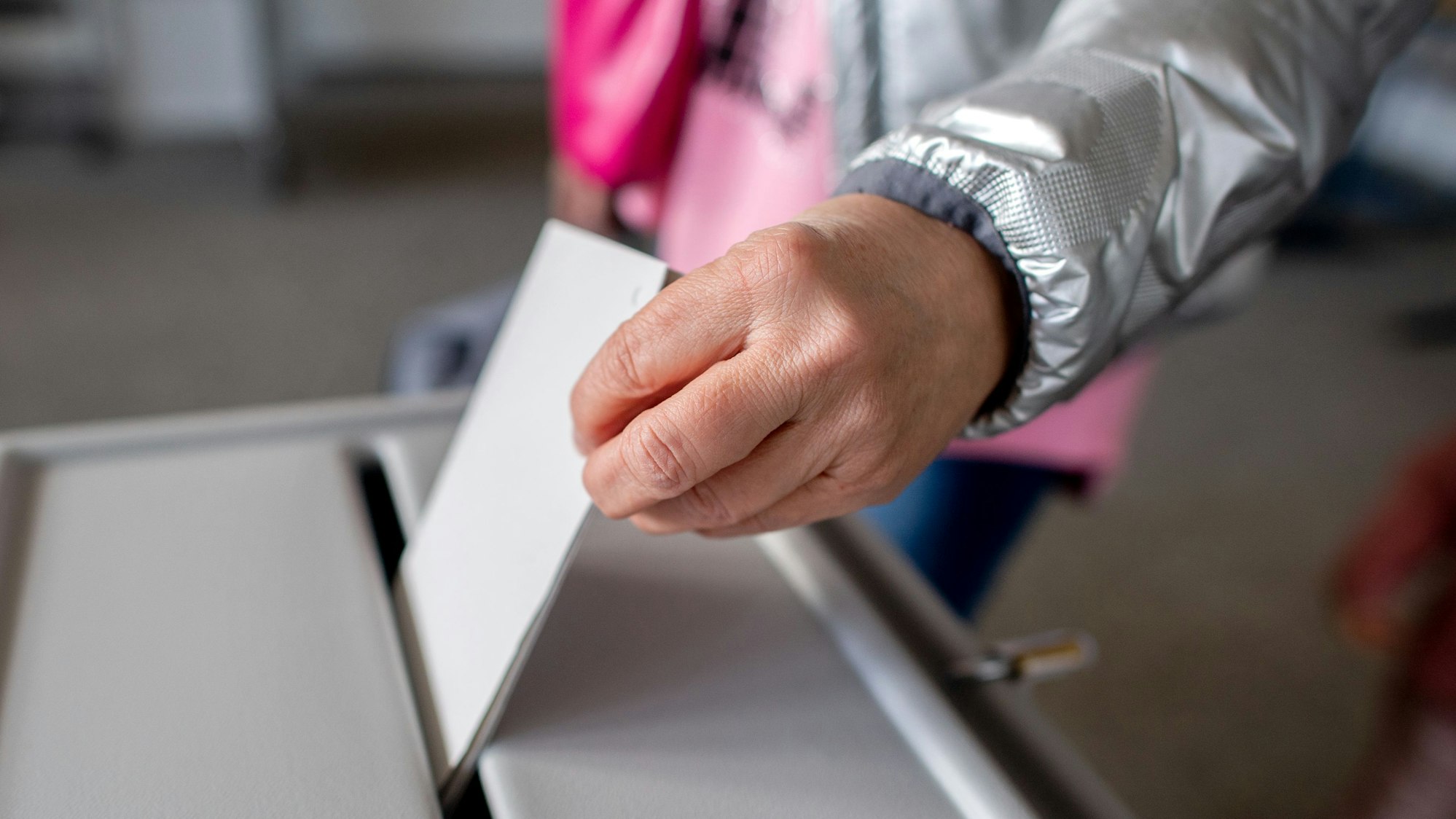 Eine Wählerin wirft in einem Wahllokal einen Stimmzettel in eine Wahlurne.