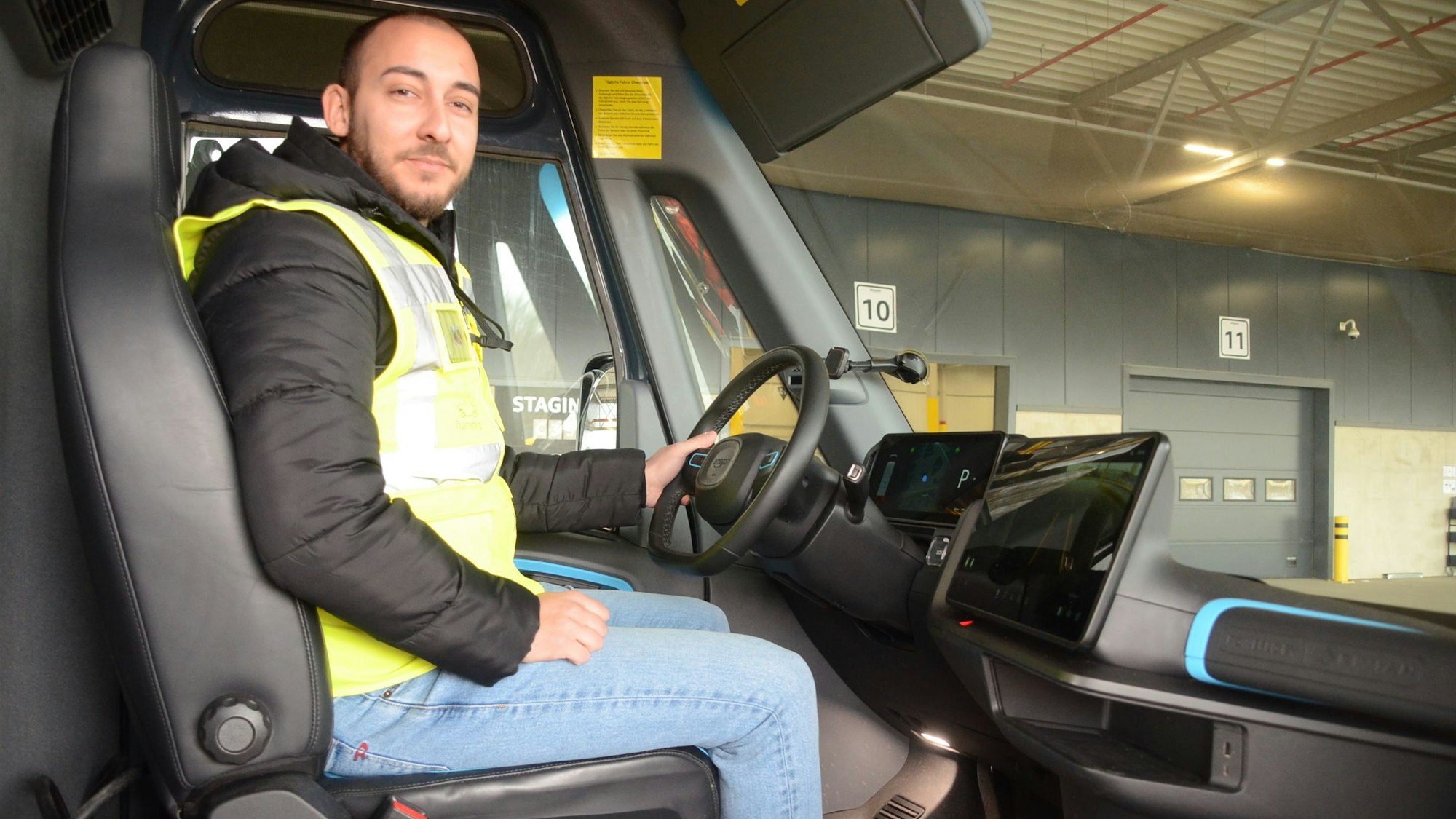 Ein Mann in einer gelben Warnweste sitzt am Steuer eines Kleintransporters.