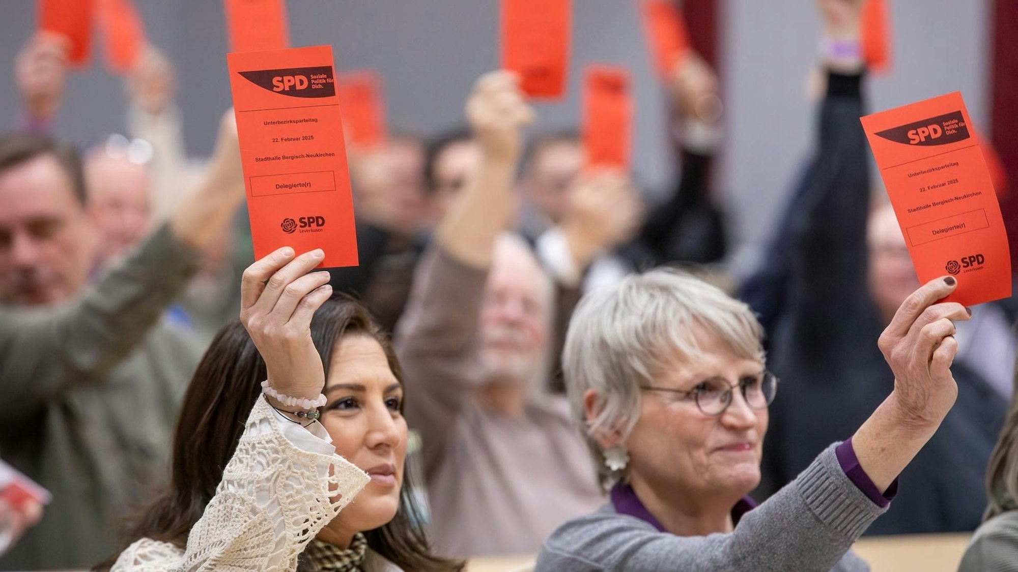 Zwei Frauen halten jeweils eine rote Abstimmungskarte hoch.