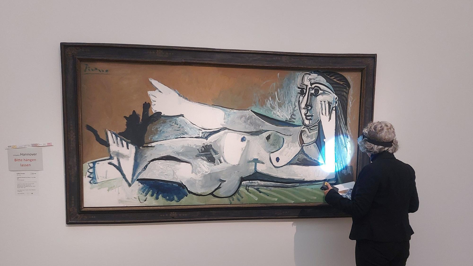 Eine Frau im dunklen Anzug steht mit dem Rücken zum Betrachter vor einem großformatigen Gemälde von Picasso.