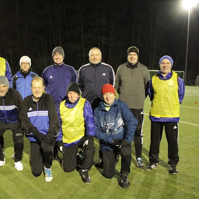 Eine Fußballmannschaft bestehend aus 11 Männern und einer Frau posiert für ein Gruppenfoto