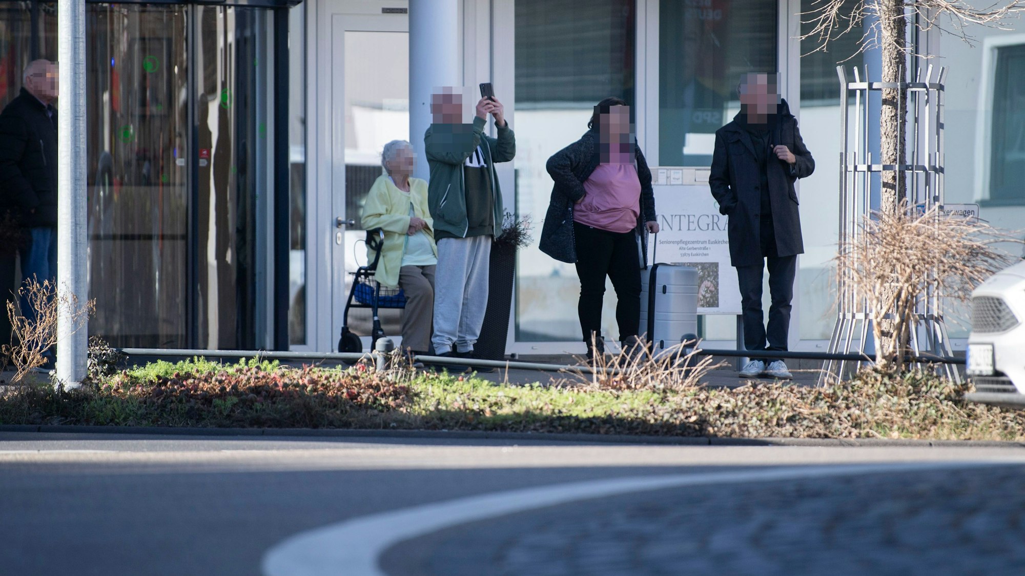 Das Bild zeigt vier Menschen, die in Richtung des Krans schauen. Ein Mann filmt das Geschehen mit einem Handy.