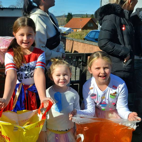 Vier kostümierte Mädchen stehen nebeneinander und breiten ihre Plastiktüten aus.