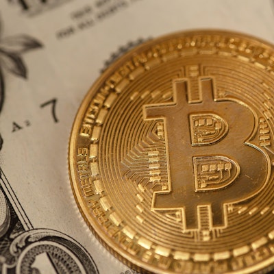 Eine goldene Bitcoin-Münze liegt auf Banknoten verschiedener Währungen. Bitcoin hat seit seinem Allzeithoch zum Amtsantritt von US-Präsident Donald Trump fast 20 Prozent an Wert in US-Dollar verloren.