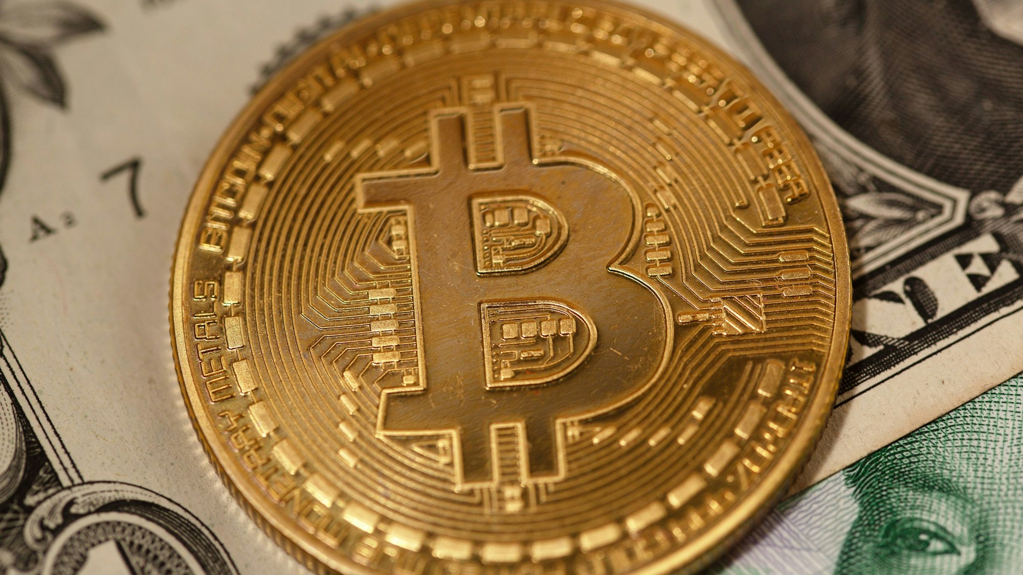 Eine goldene Bitcoin-Münze liegt auf Banknoten verschiedener Währungen. Bitcoin hat seit seinem Allzeithoch zum Amtsantritt von US-Präsident Donald Trump fast 20 Prozent an Wert in US-Dollar verloren.