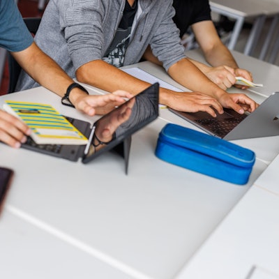 Schüler eines Gymnasiums sitzen vor einem Laptop