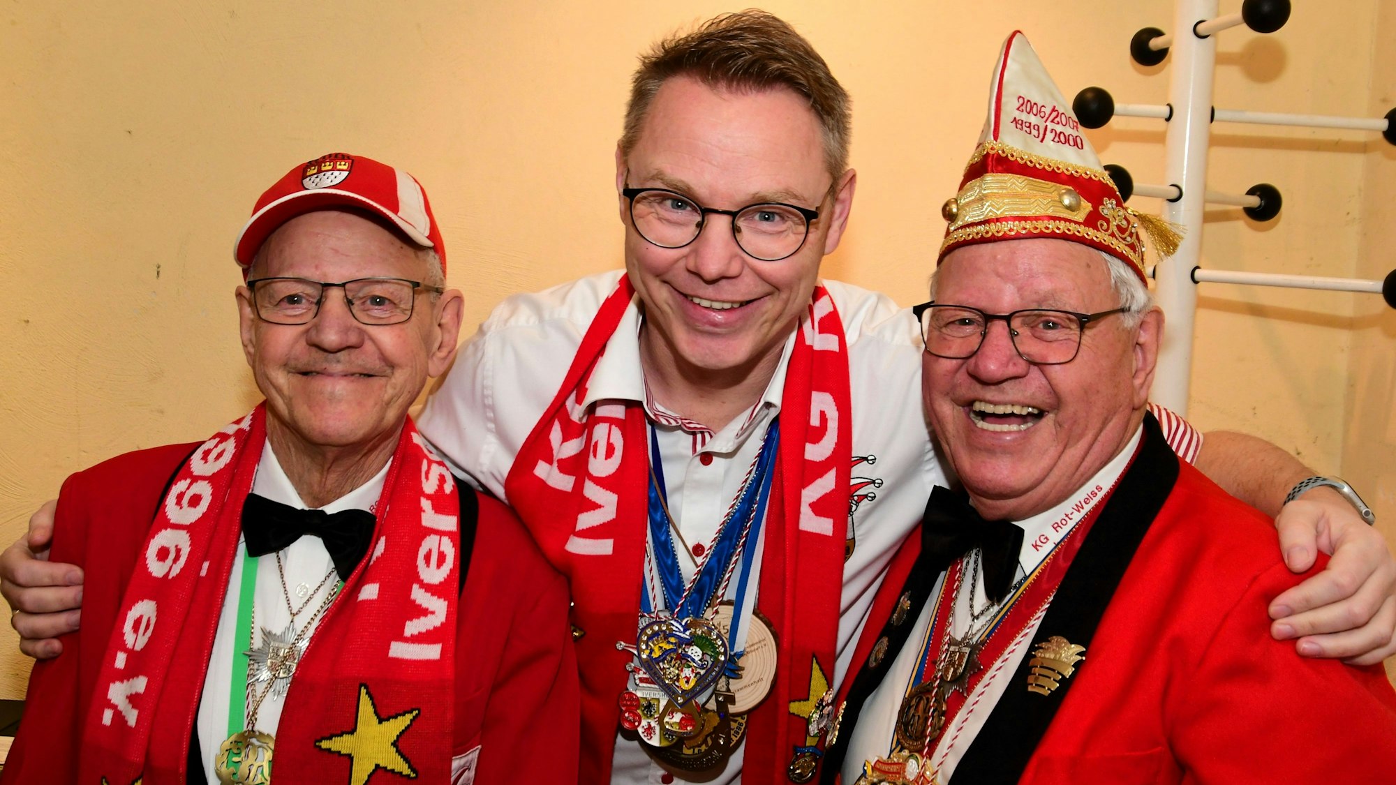 Drei Männer stehen Arm in Arm und lachen in die Kamera.