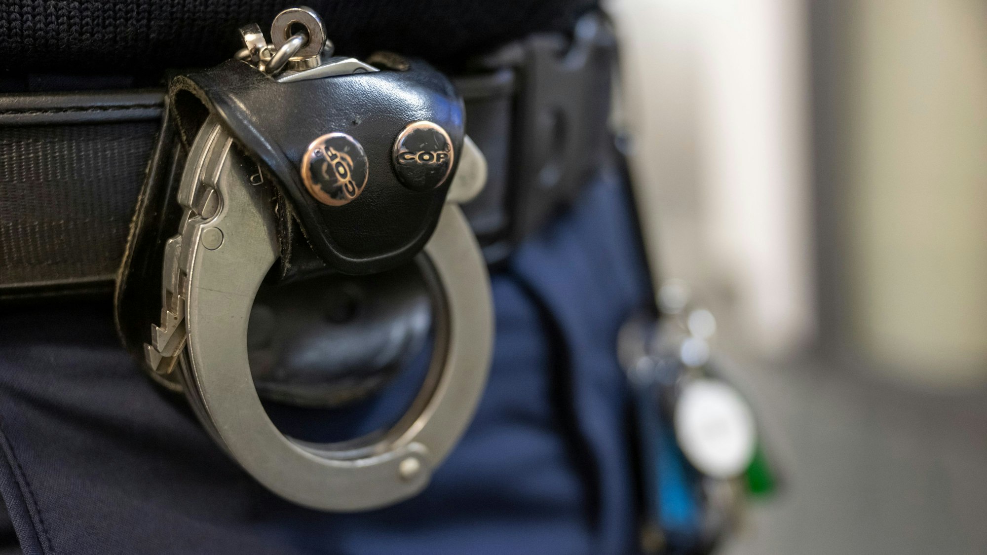 Handschellen am Gürtel eines Polizisten.