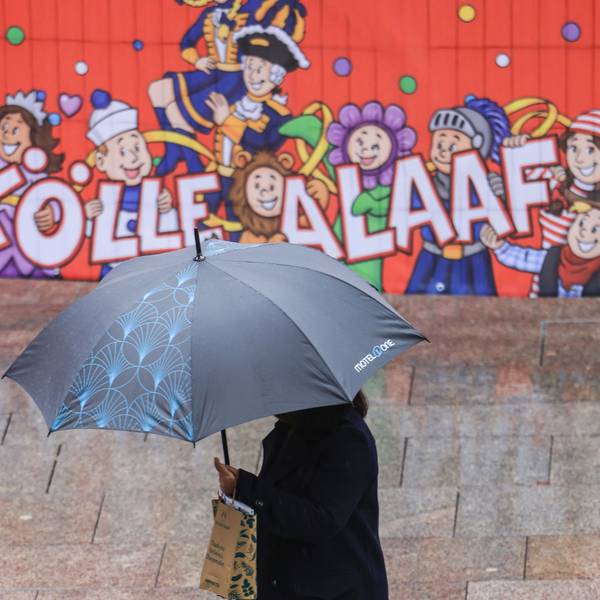 Eine Frau geht mit Regenschirm an einer Tribüne für die Karnevalsumzüge durch die Innenstadt.