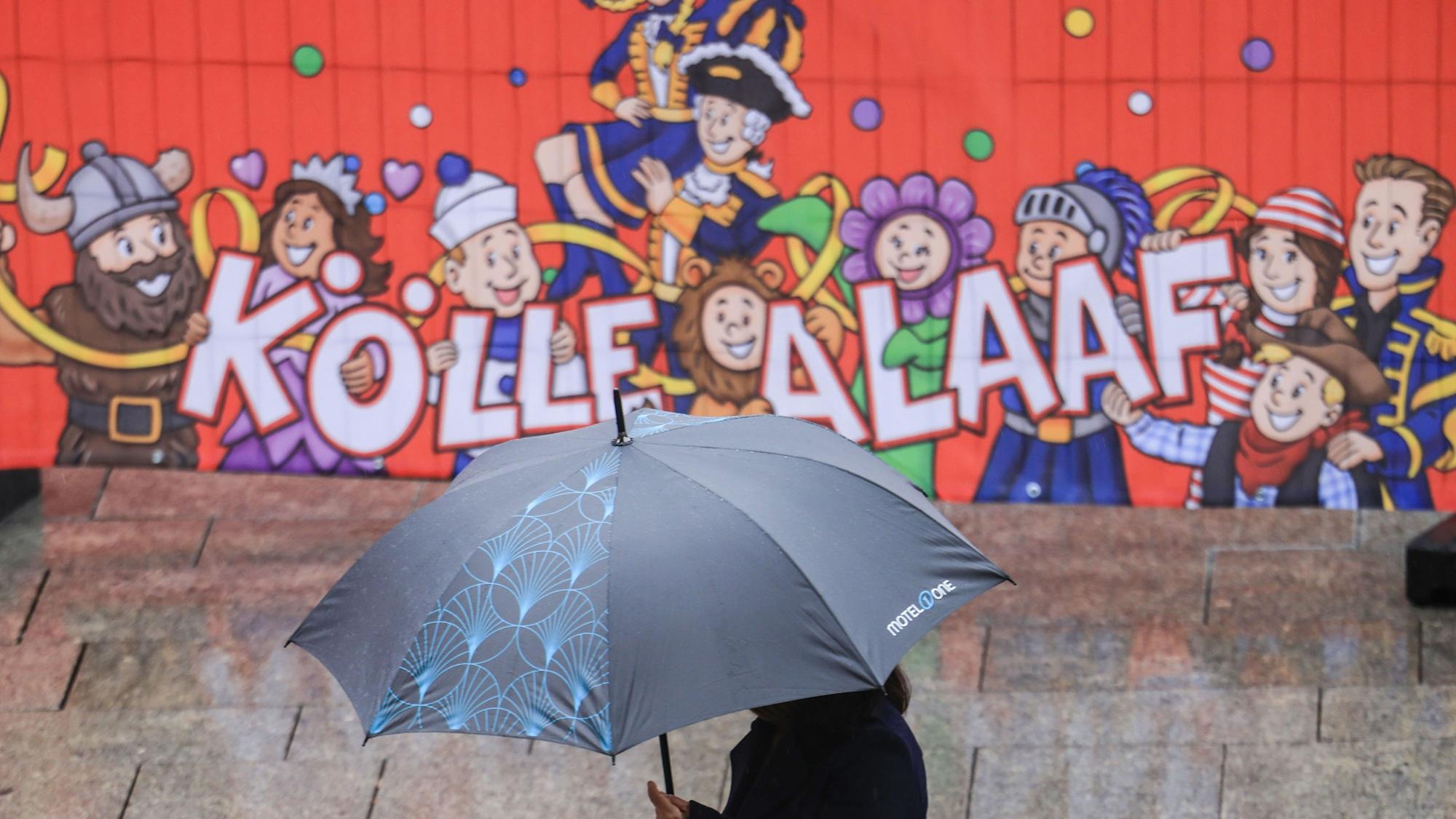 Eine Frau geht mit Regenschirm an einer Tribüne für die Karnevalsumzüge durch die Düsseldorfer Innenstadt. (Archivbild)