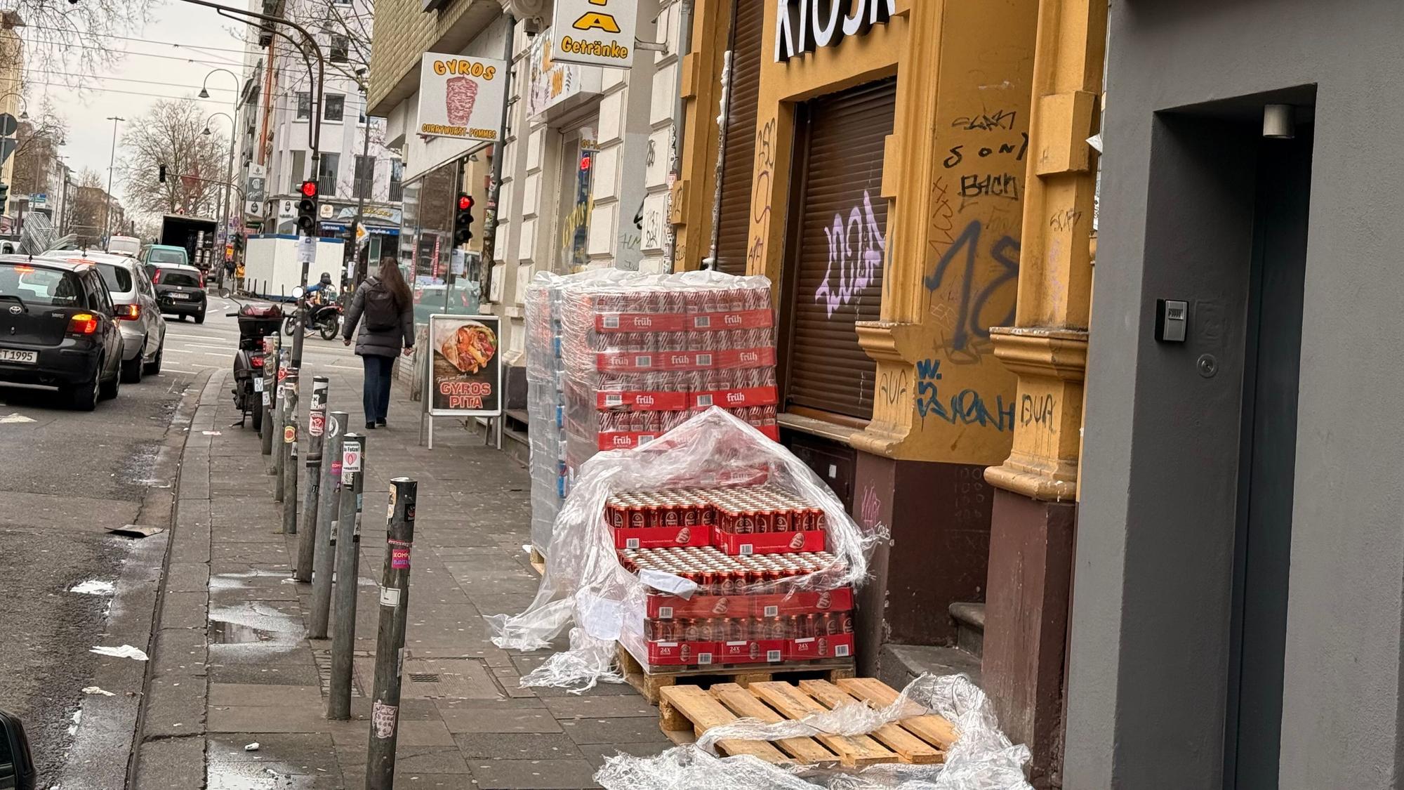Vor einem Kiosk lagern Dosen auf Europaletten